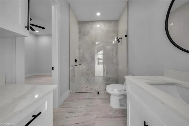 Full bath featuring recessed lighting, marble finish floor, toilet, vanity, and a marble finish shower