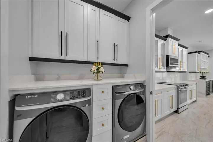 Clothes washing area featuring recessed lighting, independent washer and dryer, marble finish floor, and laundry area