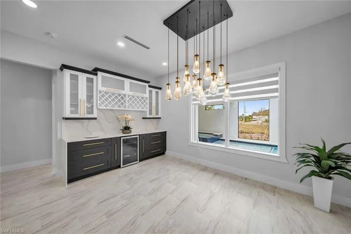 Bar featuring wine cooler, visible vents, a dry bar, decorative light fixtures, and baseboards
