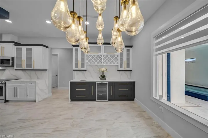 Kitchen with stainless steel appliances, wine cooler, baseboards, glass insert cabinets, and marble finish floor