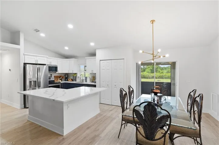 Dining room featuring suspended lighting, light wood-style floors, and lofted ceiling