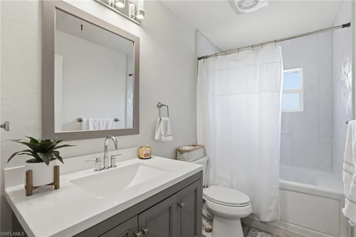 Bathroom featuring vanity and shower / bathtub combination with curtain