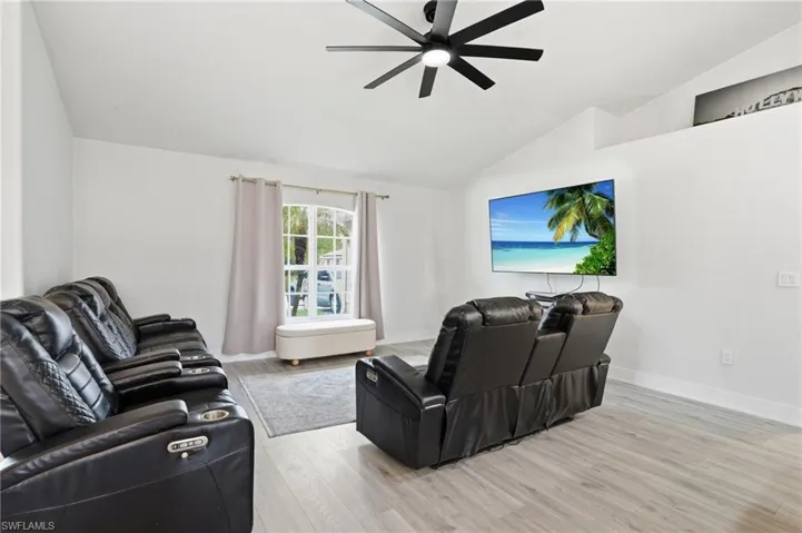Living area with light wood-style floors, lofted ceiling, and a ceiling fan