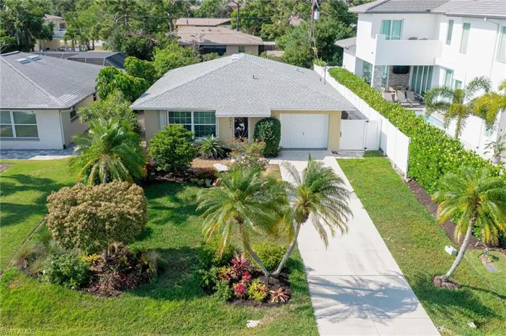 View of front of property with a front lawn, mature landscaping, and a garage