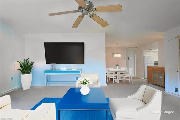 Virtually Staged: Carpeted living room with ceiling fan with notable chandelier