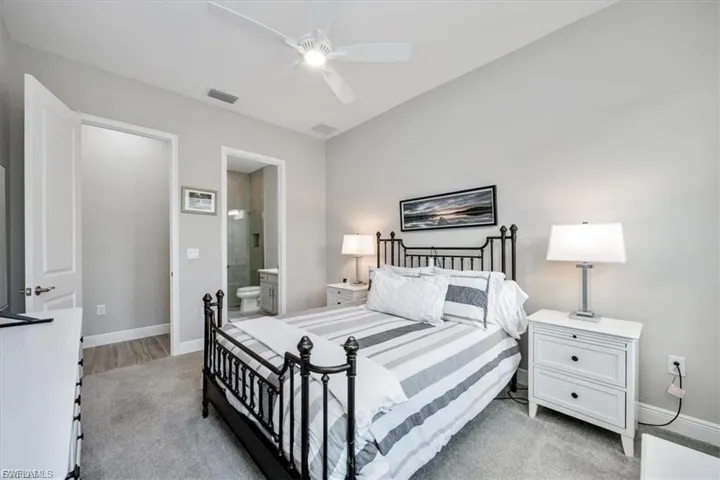 Bedroom featuring ensuite bathroom, ceiling fan, and light colored carpet