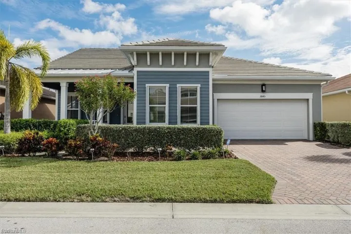 View of front facade featuring a front yard, decorative driveway, and an attached garage