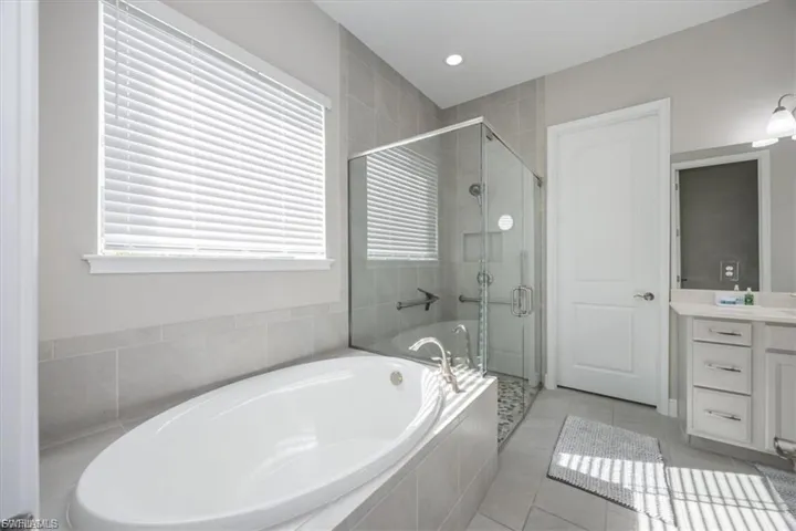 Full bathroom featuring a bath, a shower stall, light tile patterned flooring, vanity, and recessed lighting