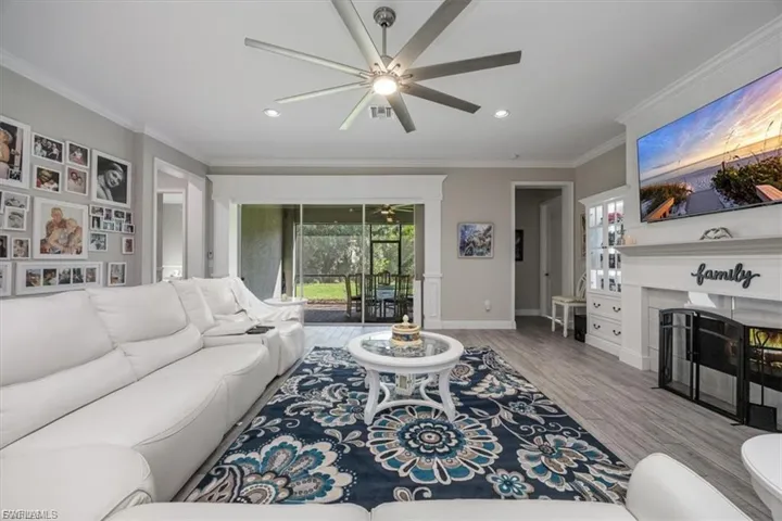 Living room featuring a fireplace, ornamental molding, light wood-type flooring, recessed lighting, and a ceiling fan