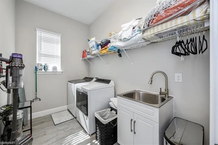 Laundry area featuring washing machine and clothes dryer, light wood-style floors, and cabinet space