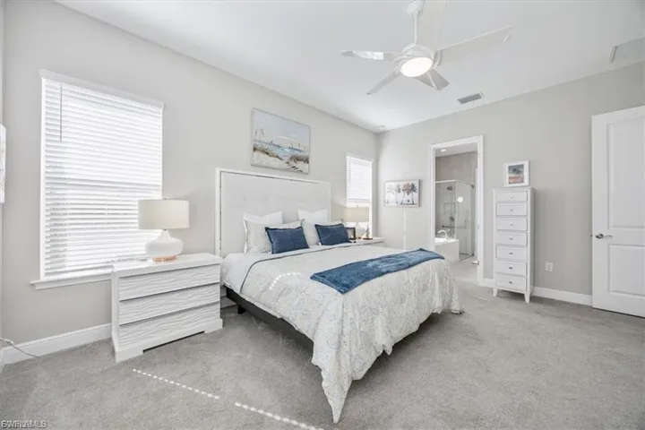 Carpeted bedroom featuring ceiling fan and connected bathroom