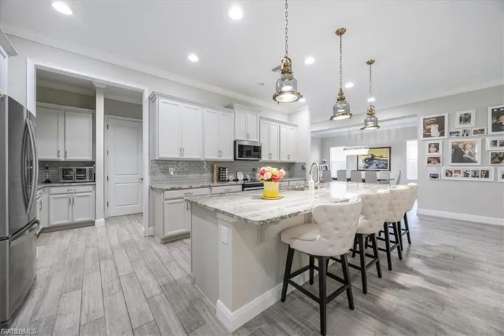 Kitchen with a kitchen bar, light wood-style floors, stainless steel appliances, tasteful backsplash, and crown molding