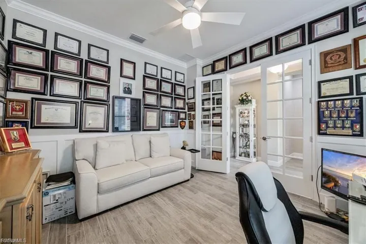 Office space with ornamental molding, french doors, light wood-style floors, a decorative wall, and ceiling fan