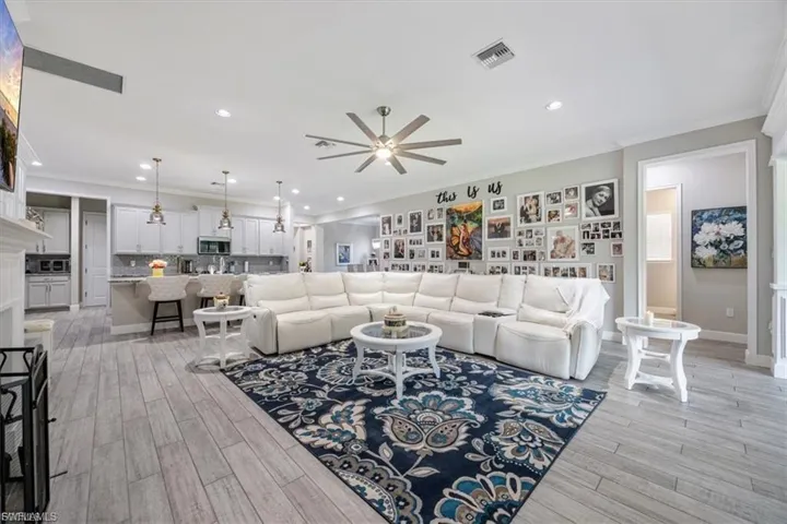 Living room featuring crown molding, recessed lighting, a ceiling fan, and light wood-style floors
