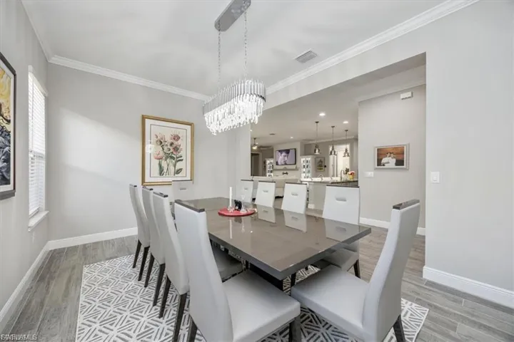 Dining space featuring ornamental molding, light wood-type flooring, and a chandelier