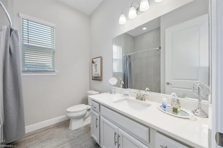 Bathroom featuring vanity, light wood-style floors, and curtained shower
