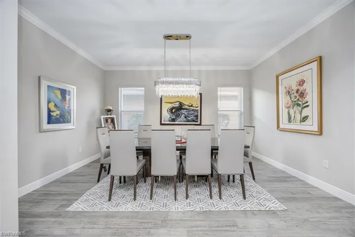 Dining room featuring light wood-style flooring, ornamental molding, and a chandelier
