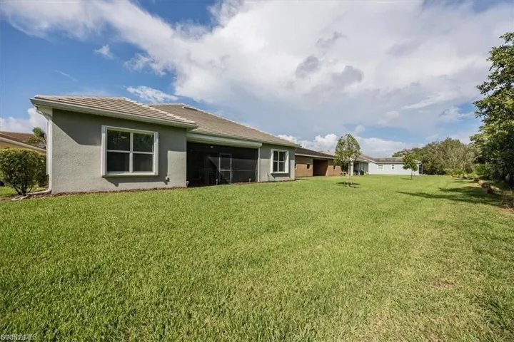 Rear view of property featuring a yard, a sunroom, and stucco siding