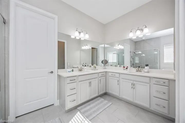 Full bathroom featuring double vanity, a shower stall, and light tile patterned floors