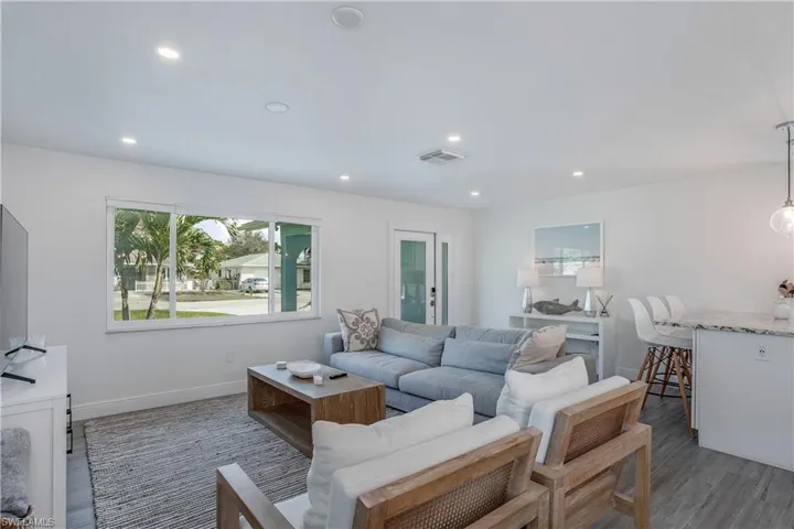 Living room featuring dark wood-style floors, baseboards, visible vents, and recessed lighting