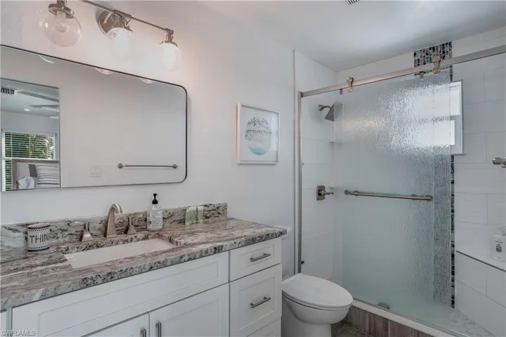 Full bathroom with toilet, a shower stall, and vanity