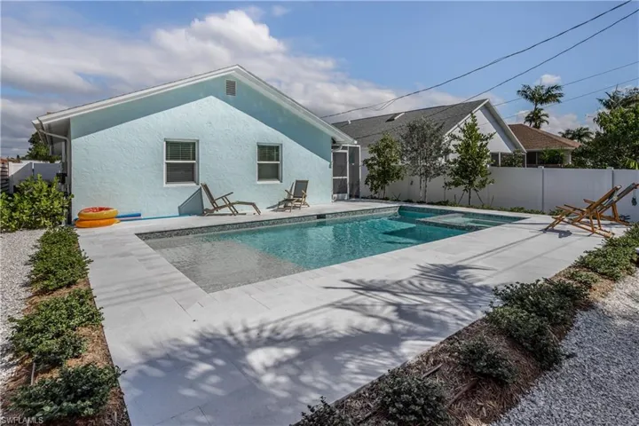 View of swimming pool featuring a pool with connected hot tub, fence, and a patio