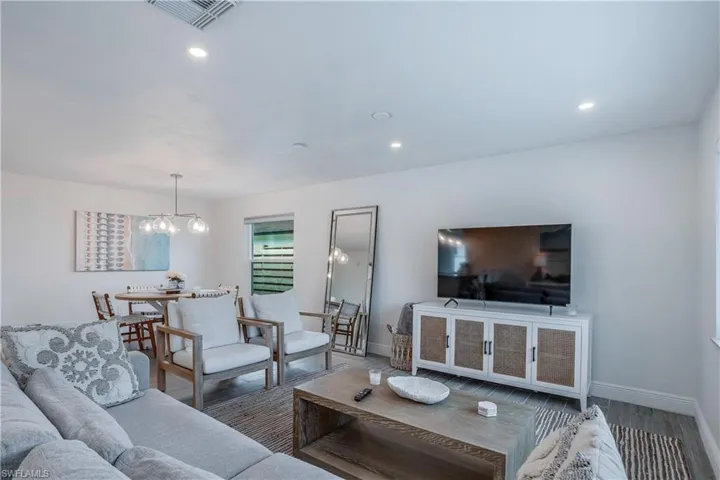 Living area featuring a chandelier, visible vents, baseboards, and wood finished floors
