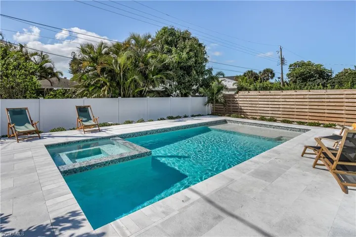 View of pool with a pool with connected hot tub, a fenced backyard, and a patio
