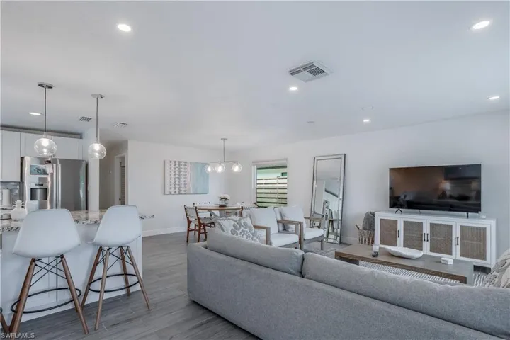 Living area featuring light wood finished floors, baseboards, visible vents, and recessed lighting