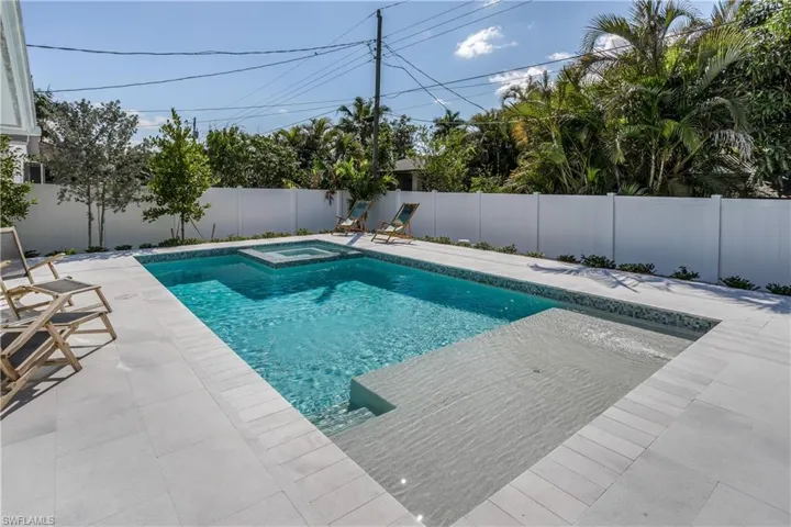 View of swimming pool featuring a patio area, a pool with connected hot tub, and a fenced backyard