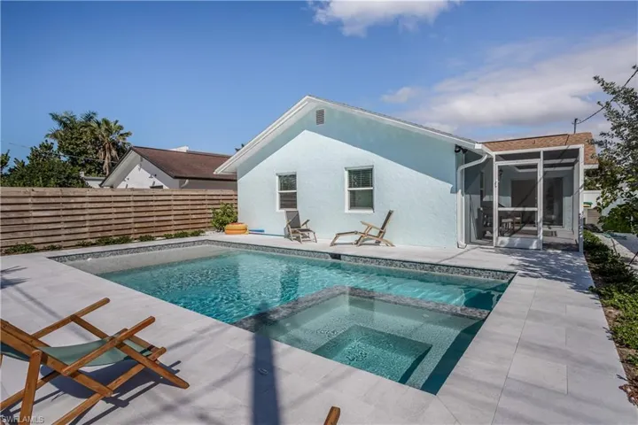 View of pool with a pool with connected hot tub, a sunroom, a patio, and fence