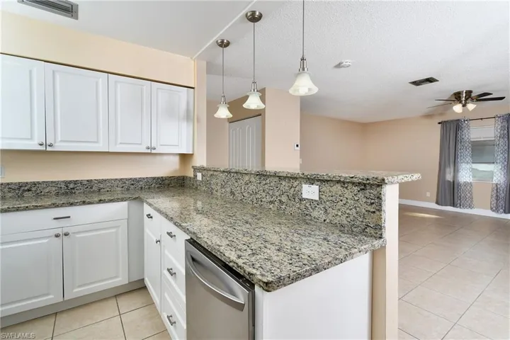 Kitchen with a textured ceiling, sink, dishwasher, range, and white cabinetry