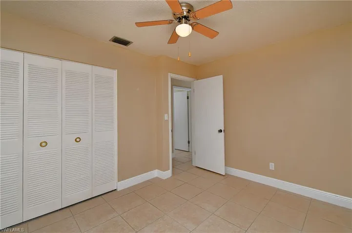 Bedroom with ceiling fan, a textured ceiling, and closet