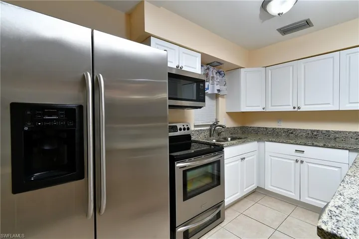 Stainless Steel Appliances. Kitchen with a textured ceiling, sink, dishwasher, range, and white cabinetry