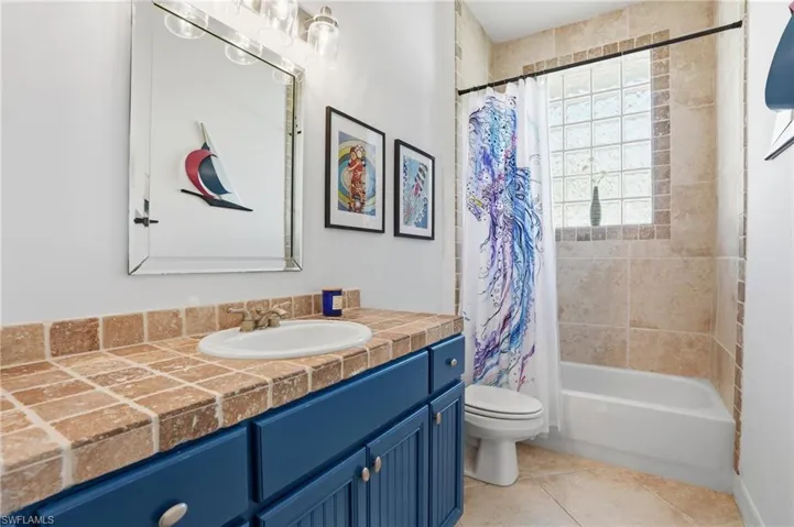 Bathroom featuring vanity, shower / bath combination with curtain, and light tile patterned floors