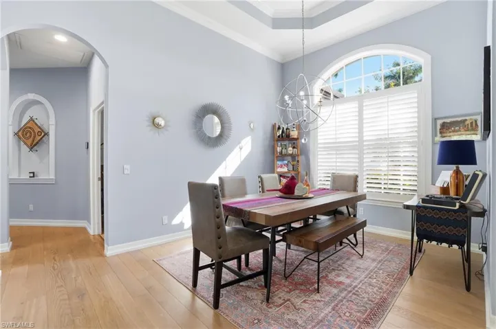 Dining space featuring crown molding, arched walkways, light wood finished floors, and a chandelier