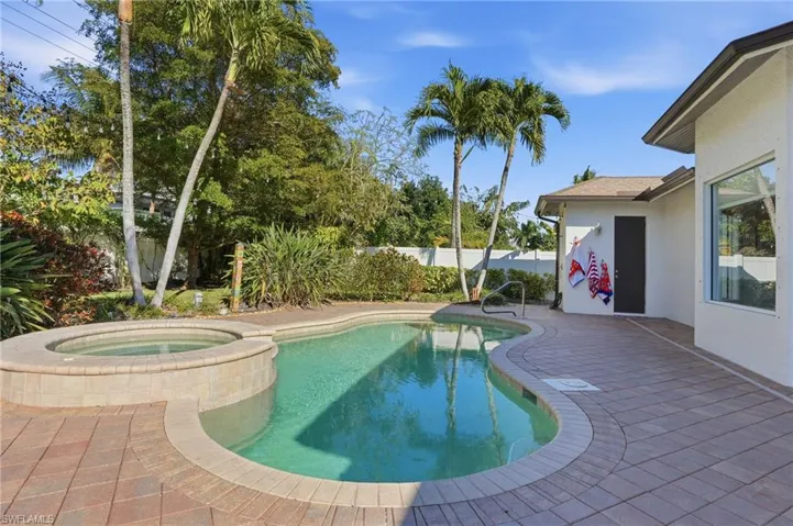 View of pool featuring a patio area, a fenced backyard, and a pool with connected hot tub
