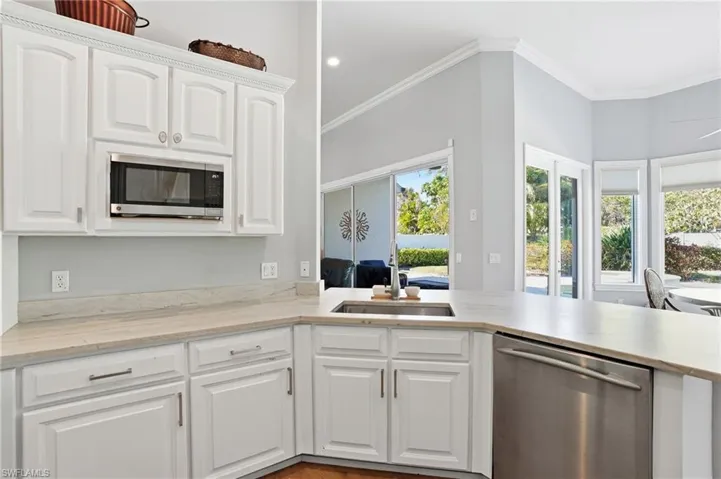 Kitchen featuring stainless steel appliances, white cabinetry, and crown molding