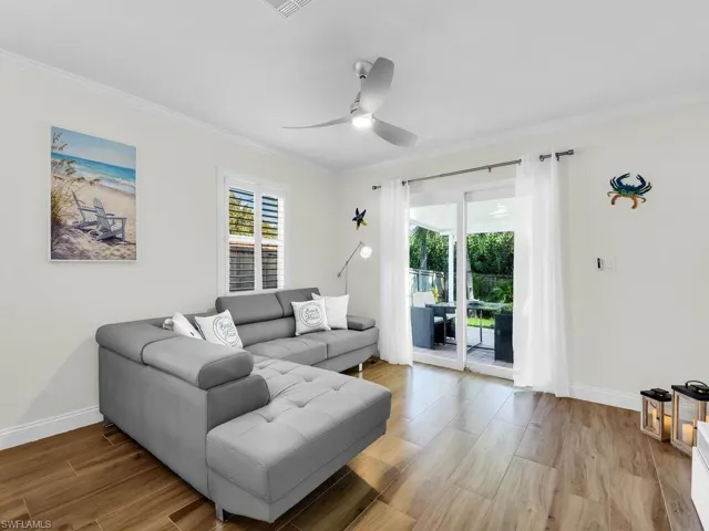 Living area featuring wood finish floors, ornamental molding, and a ceiling fan