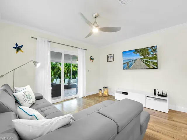 Living room with light wood-style flooring, ornamental molding, and ceiling fan