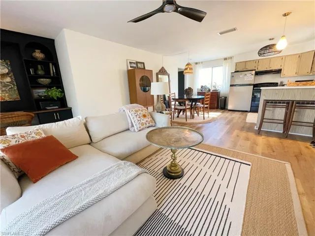 Living area featuring light wood finished floors, built in features, and a ceiling fan