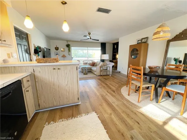 Kitchen with decorative light fixtures, light countertops, light brown cabinets, black dishwasher, and ceiling fan