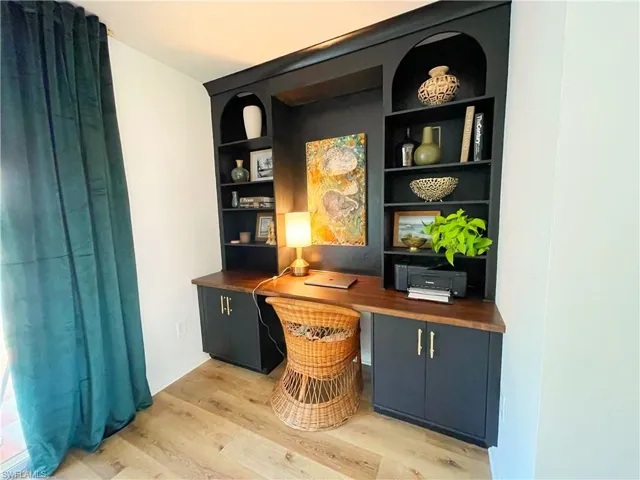 Office space with built in shelves, light wood-type flooring, and built in desk