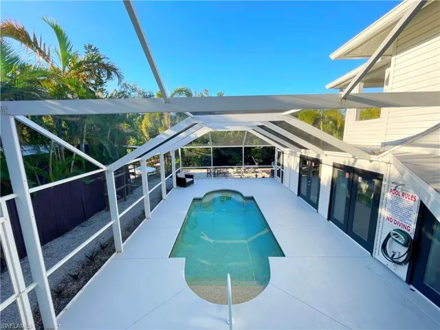 Outdoor pool with a patio area, glass enclosure, and a sunroom