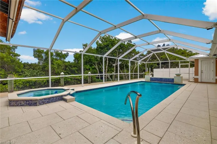 Integrated pool / hot tub with glass enclosure, a patio area, and a sunroom