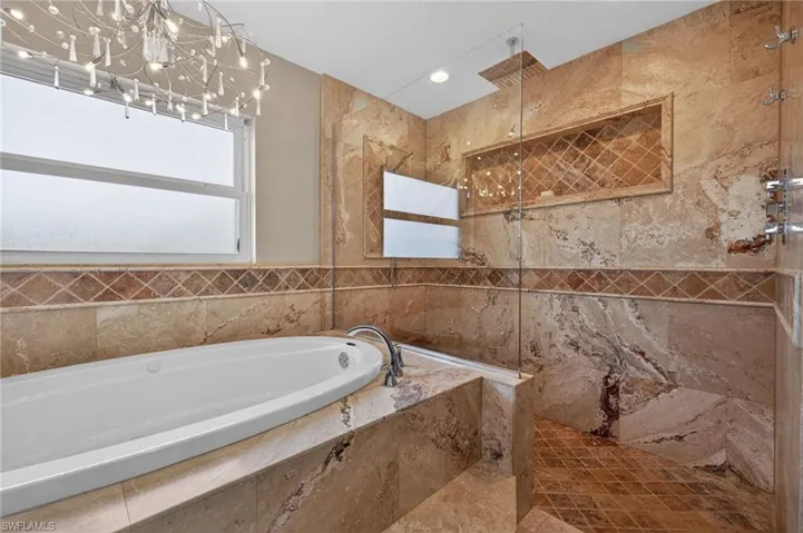 Full bath featuring a marble finish shower and a bath
