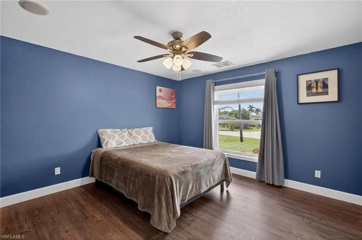 Bedroom with dark wood-type flooring, a ceiling fan, and a textured ceiling