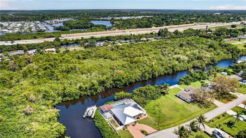 Aerial perspective of suburban area featuring a nearby body of water and a tree filled landscape