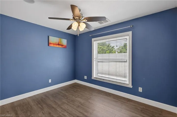 Unfurnished room with dark wood-style flooring and ceiling fan