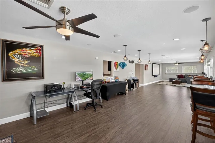 Home office in Family room area with ceiling fan, dark wood-type flooring, and a textured ceiling